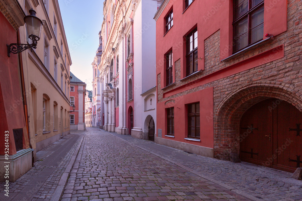 Wall mural a deserted narrow cobblestone street in the center of poznan at dawn.