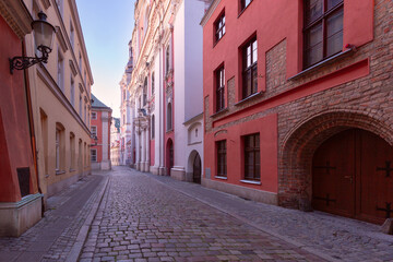 A deserted narrow cobblestone street in the center of Poznan at dawn.