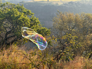 A large brightly coloured bubble floating in the air  across the open field