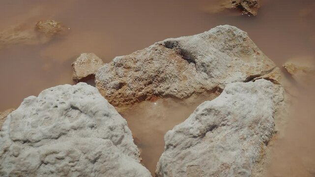 Close up view of pink saltern water with shiny, glittery rocks. Amazing nature with art surface and sun reflections on the sea surface. 