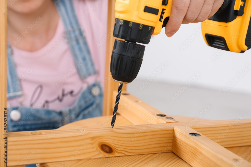 Sticker Woman with electric screwdriver assembling furniture indoors, closeup