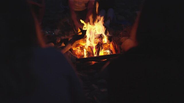 A group of friends bonding around a campfire at night, sharing stories and enjoying the warmth and coziness of the outdoors. The glowing fire highlights their togetherness and unity