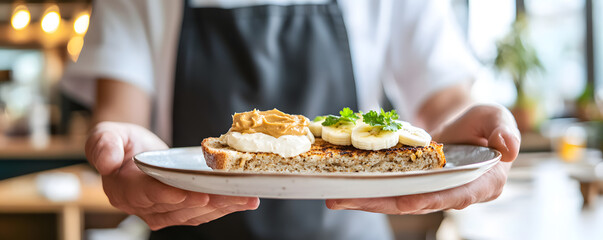 Hands present a plate of whole wheat toast with peanut butter and banana