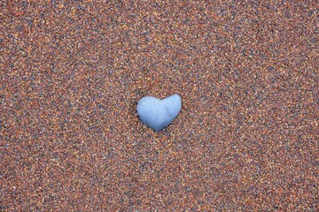 Heart shaped stone on sand background