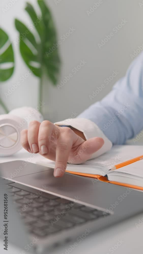 Poster An individual is focused on using a laptop and making notes in a notebook, indicating they are likely in a professional or academic environment, concentrating on tasks and responsibilities