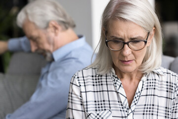 Silent mature wife thinks about relationship problems after fight with husband, sit separately on...