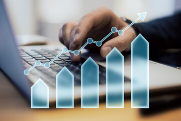 Hand typing on laptop with upward arrow and bar chart overlay symbolizing growth and financial...