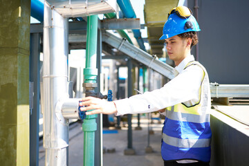 Technician checking pipeline valves or water tank area at urban industrial site