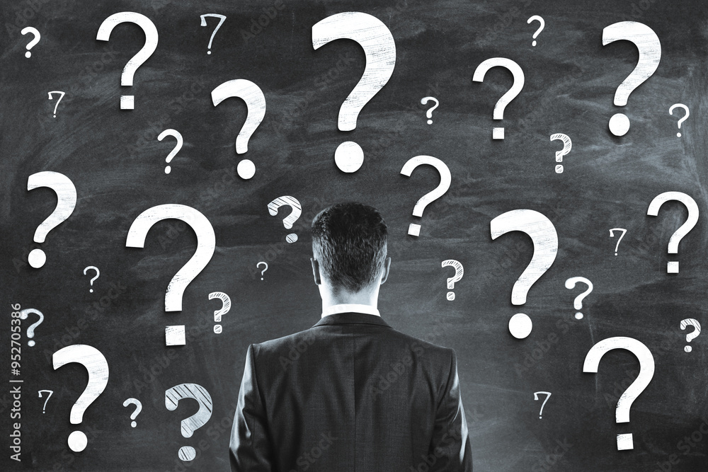 Poster Person in a business suit facing a wall filled with numerous question marks in various sizes and styles.