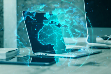 Digital holographic world map overlay on a laptop screen in a modern office environment.