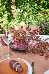 Fall table setting with pumpkins and leaves and hydrangea in brown and burgundy tones