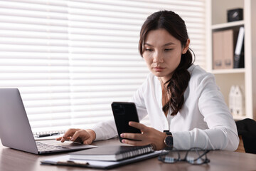 Beautiful young businesswoman using smartphone in office