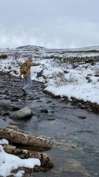 female tourist crosses a river in a national park in Finland