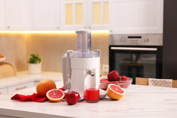 Modern juicer, fresh fruits and glass on white marble table in kitchen