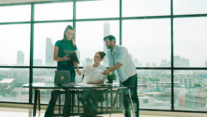 Group of happy skilled businesspeople discuss, brainstorming, sharing idea, plan, strategy about financial statistic on meeting table with laptop and statistic document. Cityscape view. Tracery