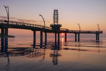 The sun beams under the dock of Brant Street Pier, as it rises under the lake during the morning at...
