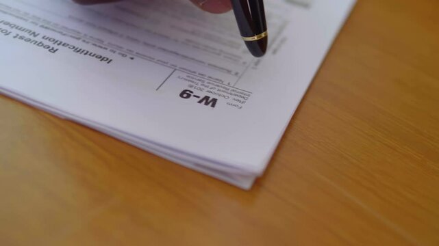 hand of black man ticking on the paper while filling out W-9 form 