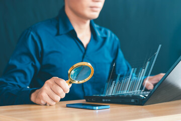 Businessman use magnifying glasses to observe and analyze a company's profits through digital virtual graphics and positive indicators.