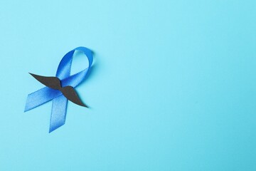 Blue ribbon and fake mustache on color background, top view with space for text. Prostate cancer awareness