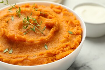Delicious mashed sweet potatoes in bowl and microgreens on table, closeup