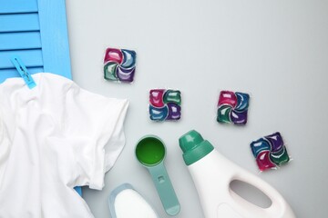 Different laundry detergents and t-shirt on grey background, flat lay