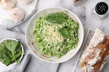 Tasty spinach risotto served on white marble table, flat lay