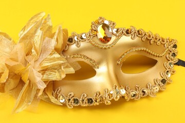 One golden carnival mask on yellow background, closeup