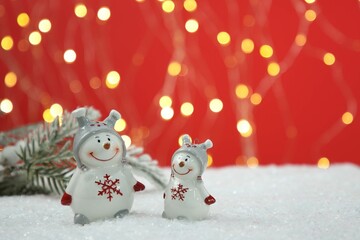 Cute decorative snowmen on artificial snow, space for text