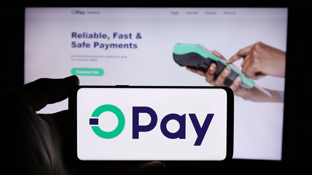 Stuttgart, Germany - 08-26-2024: Person holding cellphone with logo of Nigerian fintech company Opay Digital Services Limited in front of webpage. Focus on phone display.