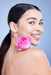 Naklejka premium Portrait, rose or woman with smile or natural beauty on blue background with flower and glow. Face, happy or girl model in studio with floral cosmetics, plants or skincare for facial results