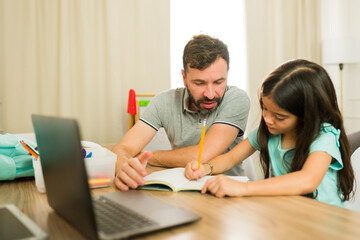 Father homeschooling her daughter and helping her solve a few math problems