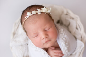 newborn baby with white wreath on white background