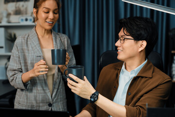 Sales managers discussing while drinking coffee cup together at over late night at home office, concept of modern working place with business report at breaking time with coworker at desk. Infobahn.