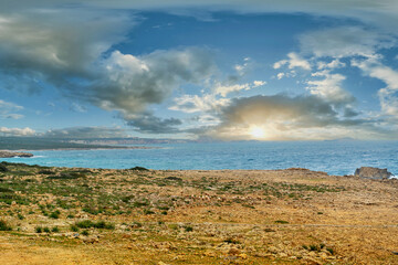 Sunrise through the clouds with sea waves hitting the rocks in the background. The easternmost tip of the Karpaz Peninsula, known as Zafer Cape. Cyprus - Kıbrıs