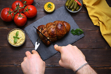 male hands cutting baked meat on the background of a wooden table