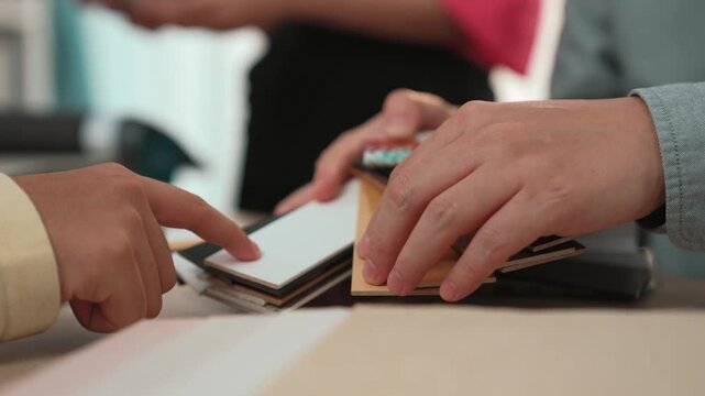 Slow motion hand closeup of professional architect and interior designer presenting material and color from color palette for interior house design based on customer oversee and supervised. Variegated