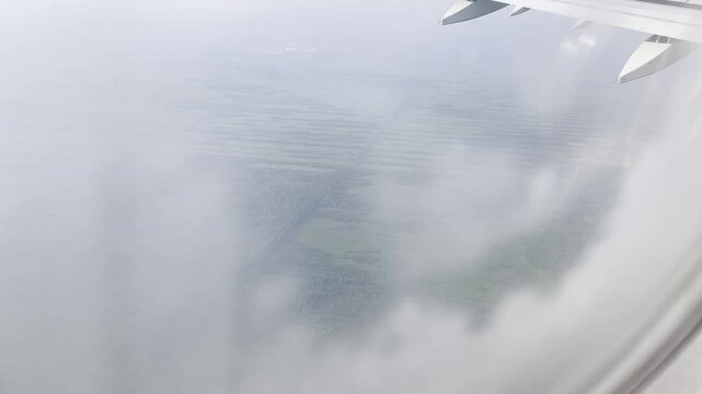 View of green agricultural fields through clouds in plne porthole in summer