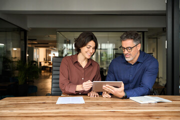 Professional business people, two happy busy mid age business man and young woman executives...