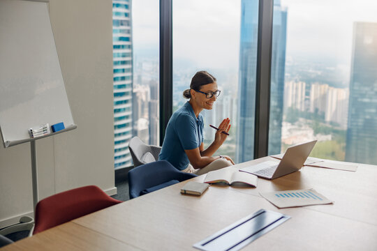 A skilled businesswoman is on a video call from a modern conference room discussing important matters
