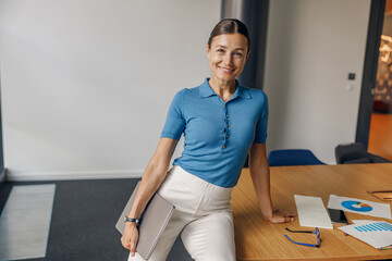 A selfassured businesswoman is confidently standing in a bright, modern office environment showcasing professionalism