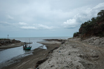 A serene scene of a traditional fishing boat gliding through calm waters during early morning hours in Prachuap Khiri Khan, Thailand. 