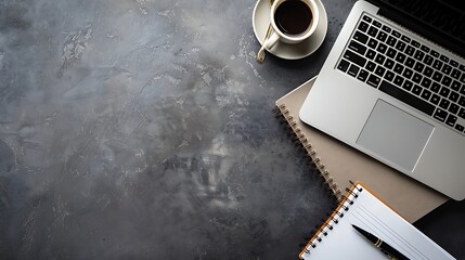 Overhead view of a business desk featuring a laptop notebook pen and coffee cup with ample empty space on the right side for text or additional content