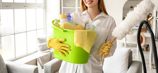 Young woman with bucket of cleaning supplies at home