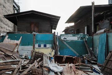 an abandoned wooden house in a state of disrepair, surrounded by scattered debris and broken materials.