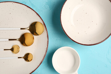 Clean plates and set of golden cutlery on blue grunge table