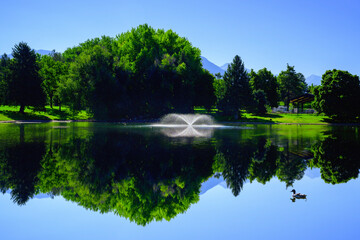 Tranquil water reflections of the mountain and forest on Sugar House Pond in Salt Lake City, Utah:...
