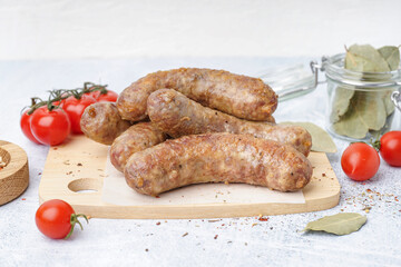 Wooden board of tasty homemade sausages on light background