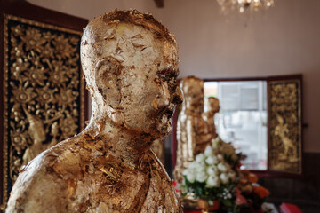 Close-up of a gold leaf-covered Buddha statue inside a Thai temple. 