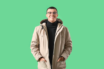 Young man in winter clothes on green background