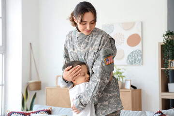 Female soldier with her little son hugging at home